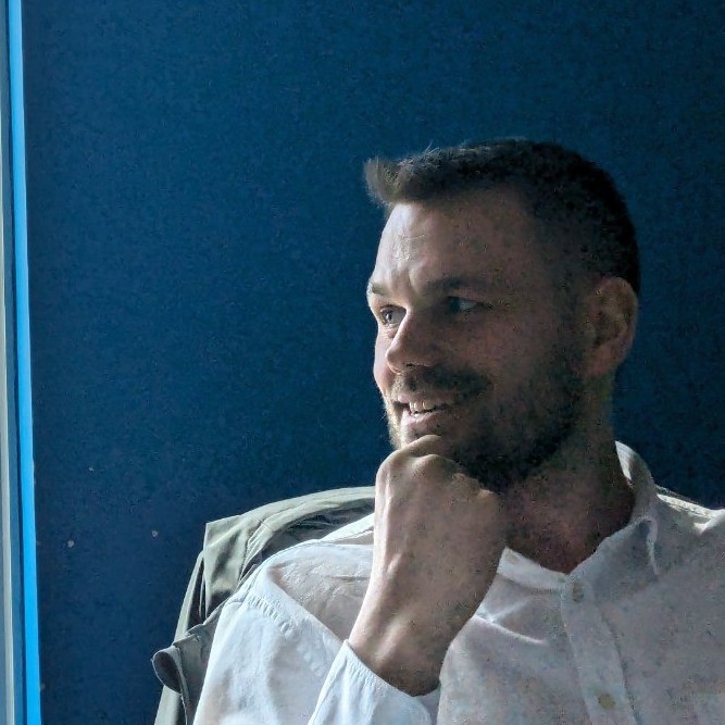 Valentin Ganchev smiling in a white shirt with the lovely sea in the background